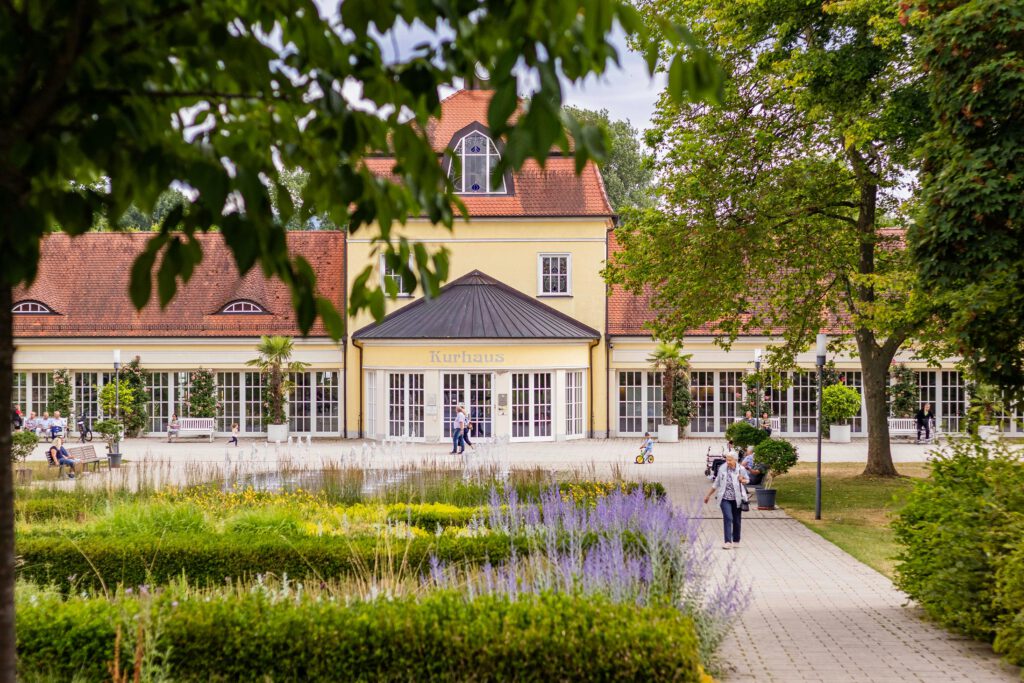 Scenic view of a Kurhaus building surrounded by vibrant gardens and walking paths.
